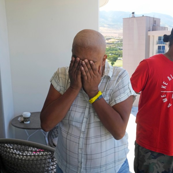 Makalea Ahhee, left, tears up while her husband, JP Mayoga, right, a chef at the Westin Maui, Kaanapali, stand on their balcony at the hotel and resort, Sunday, Aug. 13, 2023, near Lahaina, Hawaii. About 200 employees are living there with their families in the resort. Officials urge tourists to avoid traveling to Maui as many hotels prepare to house evacuees and first responders on the island where a wildfire demolished a historic town and killed dozens of people. (AP Photo/Rick Bowmer)